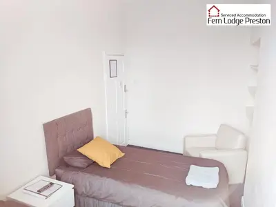 a small bedroom with a bed and a chair at 4 Bedroom House at Fern Lodge Preston Serviced Accommodation - Free WiFi & Parking in Preston