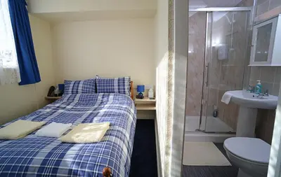 a bedroom with a bed and a shower and a sink at Lynmoore Guest House in Blackpool