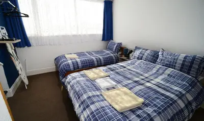 two beds in a bedroom with blue and white sheets at Lynmoore Guest House in Blackpool
