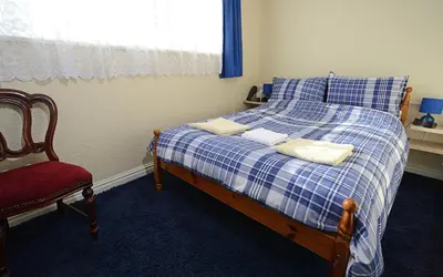 a bedroom with a blue and white bed and a red chair at Lynmoore Guest House in Blackpool
