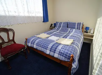 a bedroom with a bed and a red chair at Lynmoore Guest House in Blackpool