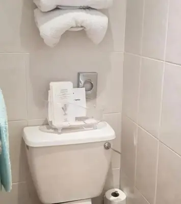 a white bathroom with a toilet and rolls of toilet paper at OYO Wynnstay Hotel in Blackpool