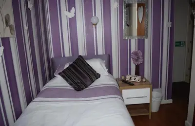 a bedroom with a bed with a purple and white striped wall at OYO Wynnstay Hotel in Blackpool
