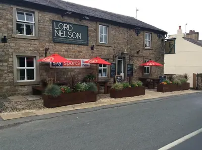 a restaurant with red umbrellas in front of a building at The Lord Nelson Inn B&B in Langho