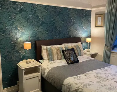 a bedroom with a bed and a green wall at EsJays at Knowles House in Lytham St Annes