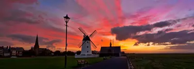 a sunset with a windmill in front of a building at EsJays at Knowles House in Lytham St Annes