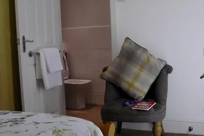 a bedroom with a chair with a pillow on it at Pilkingtons Guest House Accrington in Accrington