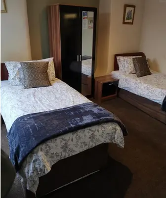a bedroom with two beds and a mirror at Pilkingtons Guest House Accrington in Accrington