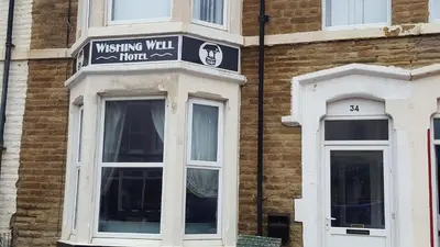 a building with a sign for a wishing wall hotel at Wishing Well Guest House in Blackpool