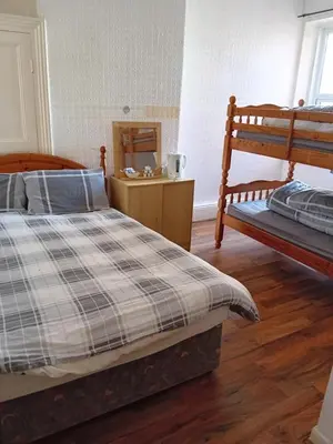 a bedroom with two bunk beds and a wooden floor at Wishing Well Guest House in Blackpool