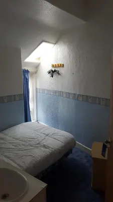 a small room with a bed and a sink at Wishing Well Guest House in Blackpool