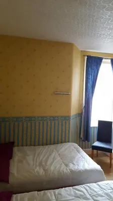 a bedroom with a bed and a window and a chair at Wishing Well Guest House in Blackpool