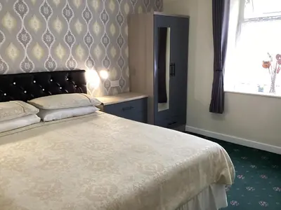 a bedroom with a large bed and a window at Myrtle house in Blackpool