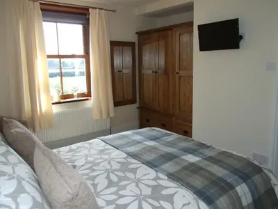 a bedroom with a bed and a tv on the wall at Stanley Lodge Farmhouse in Cockerham