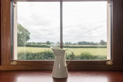 a white vase sitting on a table in front of a window at Stanley Lodge Farmhouse in Cockerham