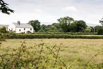 a white house in the middle of a field at Stanley Lodge Farmhouse in Cockerham