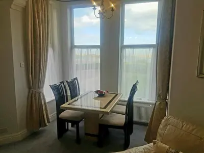 a dining room with a table and chairs and a window at Promenade Apartments in Southport