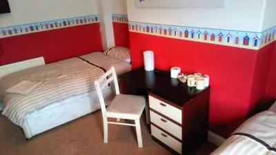 a bedroom with two beds and a desk with a chair at The Driftwood Hotel in Blackpool
