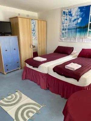 a bedroom with two beds with red sheets and a tv at The Blue Moon in Blackpool