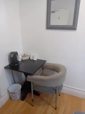 a desk with a chair and a table with a mirror at MyRoomz Orchid Hotel in Blackpool