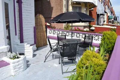 a table and chairs with an umbrella on a patio at MyRoomz Orchid Hotel in Blackpool