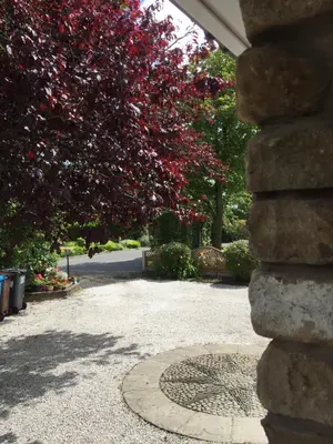 a tree with red flowers next to a manhole at Merok Lodge in Great Eccleston
