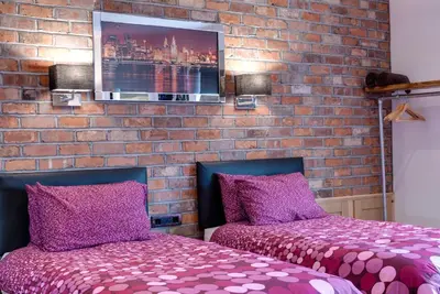 a bedroom with two beds and a brick wall at Tom Thumb Apartments in Liverpool