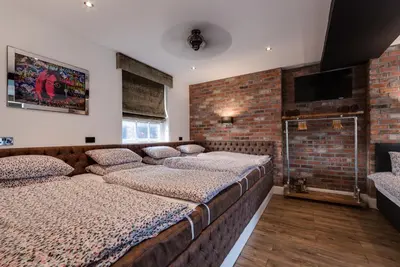 a bedroom with two beds and a brick wall at Tom Thumb Apartments in Liverpool