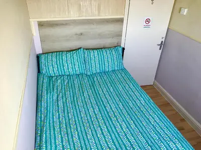 a bed in a small room with green sheets at Aparthotel Coniston in Blackpool