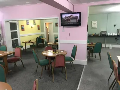 a room with tables and chairs and a tv on a wall at The Orbiston in Blackpool