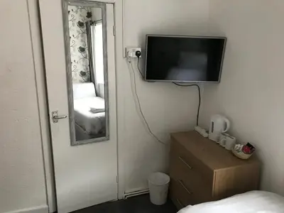 a room with a tv on the wall and a mirror at The Orbiston in Blackpool