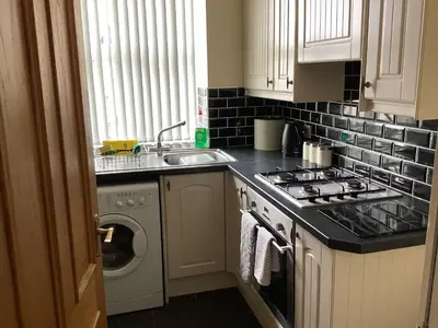 a kitchen with a stove and a sink and a washing machine at Jeffersons Abbey Road Serviced Apartments in Barrow in Furness