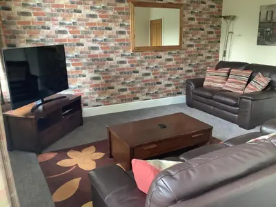 a living room with a couch and a television at Jeffersons Abbey Road Serviced Apartments in Barrow in Furness