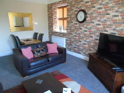 a living room with a couch and a brick wall at Jeffersons Abbey Road Serviced Apartments in Barrow in Furness