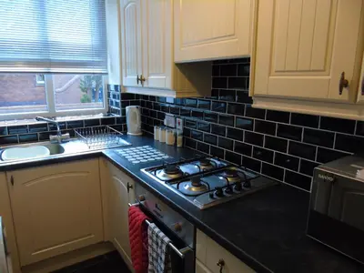 a kitchen with a stove top oven next to a sink at Jeffersons Abbey Road Serviced Apartments in Barrow in Furness