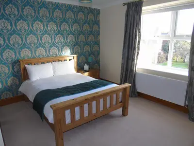 a bedroom with a wooden bed with blue and green wallpaper at Jeffersons Abbey Road Serviced Apartments in Barrow in Furness