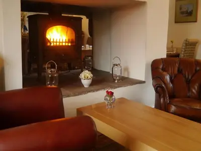 a living room with a fireplace and a table and chairs at 3 Millstones Inn in West Bradford