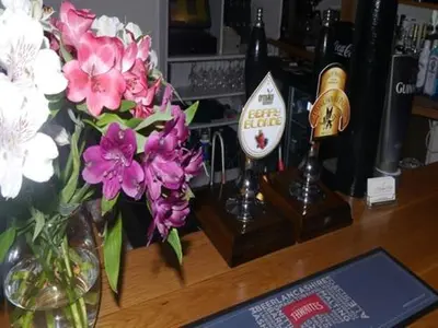 a desk with flowers in a vase on it at 3 Millstones Inn in West Bradford