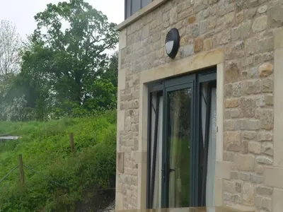 a stone building with a clock on the side of it at 3 Millstones Inn in West Bradford