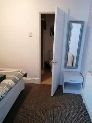 a bedroom with a bed and a mirror and a door at The Kirkview in Blackpool