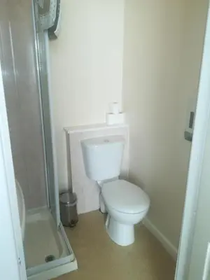 a white bathroom with a toilet and a shower at The Kirkview in Blackpool