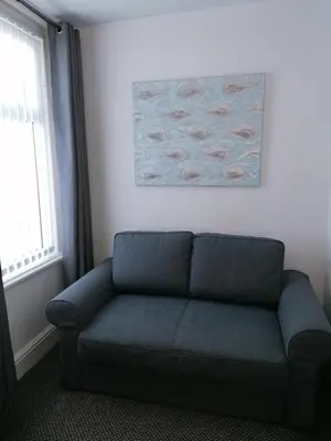 a blue couch in a room with a painting on the wall at The Kirkview in Blackpool