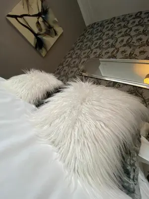 a white furry pillow on a bed with a laptop at Mayfair Hotel in Blackpool