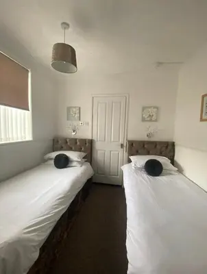 two beds in a room with white sheets at Mayfair Hotel in Blackpool