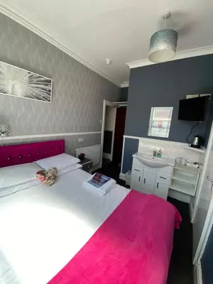 a bedroom with a large bed with a pink blanket at Mayfair Hotel in Blackpool