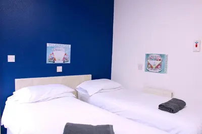 two beds in a room with a blue wall at The Regency Hotel in Blackpool