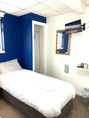 two beds in a room with a blue wall at The Regency Hotel in Blackpool