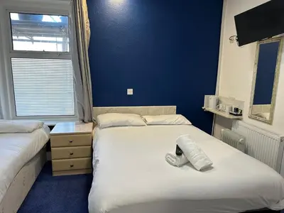a bedroom with two beds and a blue wall at The Regency Hotel in Blackpool