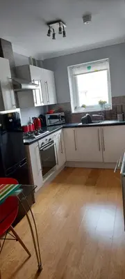 a kitchen with white cabinets and a wooden floor at Mersey View, Two Bedroom Apartment, Liverpool in Waterloo