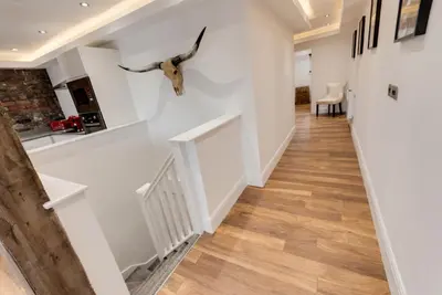 a hallway with white walls and wooden floors at The Picture House Apartments in Liverpool